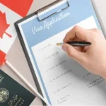 يد تكتب في استمارة طلب تأشيرة كندا بجانب جواز سفر جزائري وعلم كندي، يمثل عملية تقديم ملف فيزا كندا للجزائريين