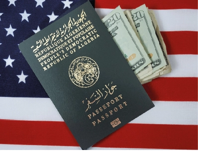 جواز سفر جزائري ومبلغ من الدولار الأمريكي فوق العلم الأمريكي، صورة تعبيرية عن فيزا أمريكا للجزائريين.