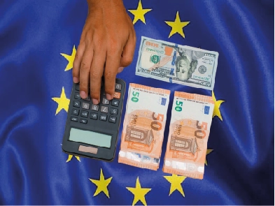 يد تستخدم آلة حاسبة بجانب أوراق نقدية من فئة 50 يورو وورقة دولار أمريكي، على خلفية علم الاتحاد الأوروبي، تمثل حساب تكلفة ورسوم فيزا شنغن. Exporter vers Sheets